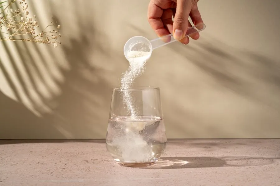 person puring nutritious powder supplement into water
